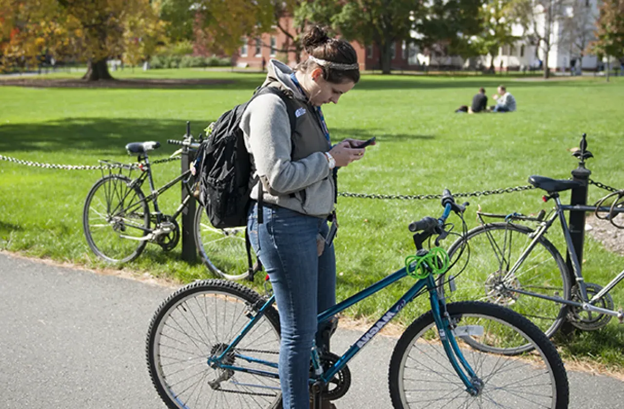 Girl looking at cellphone while riding a bike